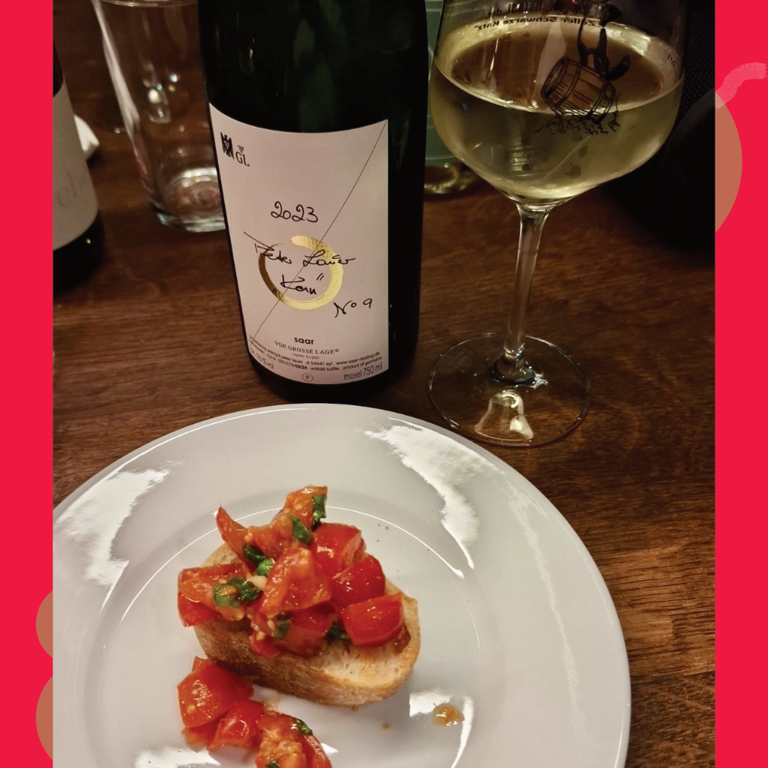 Weinglas, Weinflasche und Bruschetta mit Tomaten auf einem Holztisch bei einer Rebenreise Mosel Weinprobe in der Weinlounge Zell.